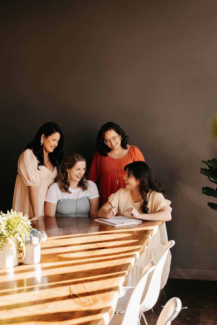 wichita small business mentor consultant sits at table with three other women and smiles while taking notes